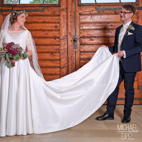 Bräutigam hält Schleppe der Braut – Hochzeitsfotografie